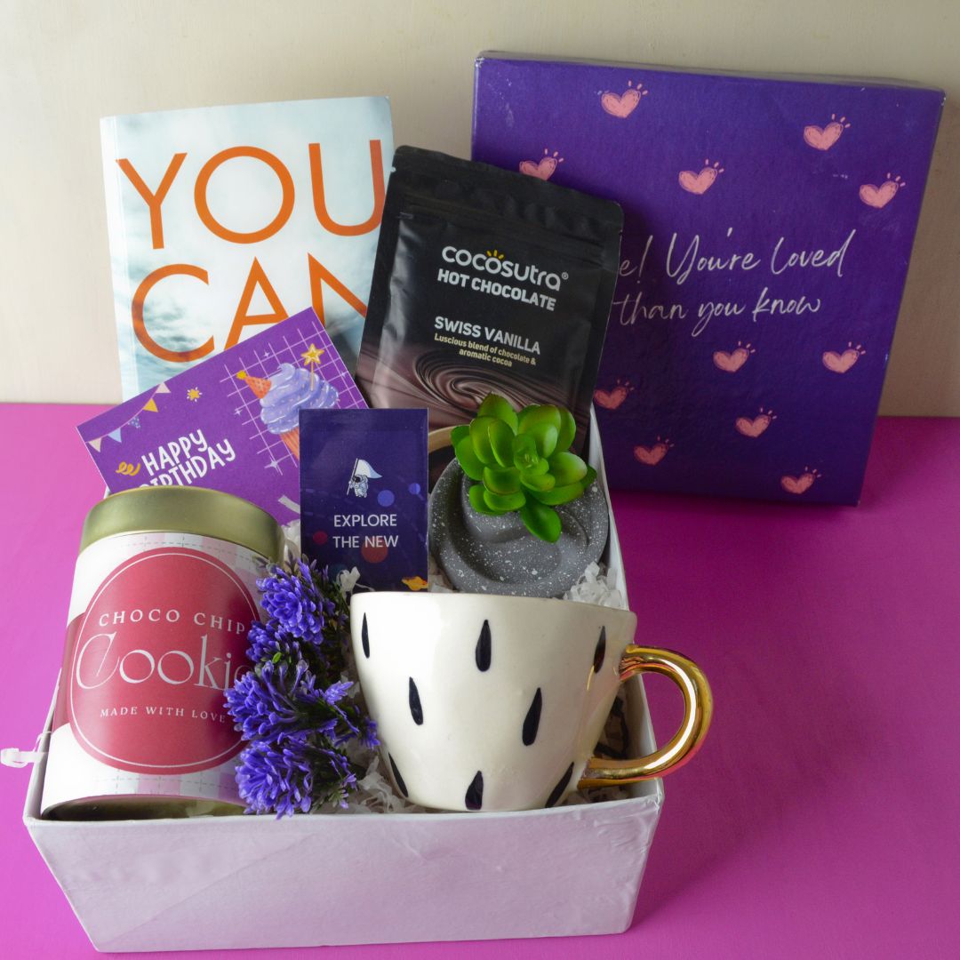 Birthday Bookworm Hamper : This Hamper Contains : “You Can” Bestselling book, Magnetic Bookmark , Ceramic cup with golden handle, Hot chocolate pack, Choco chip cookie tin ,Circular artificial Succulent plant ,Happy Birthday card , Flower gypsies bunch and Surprise heart Box