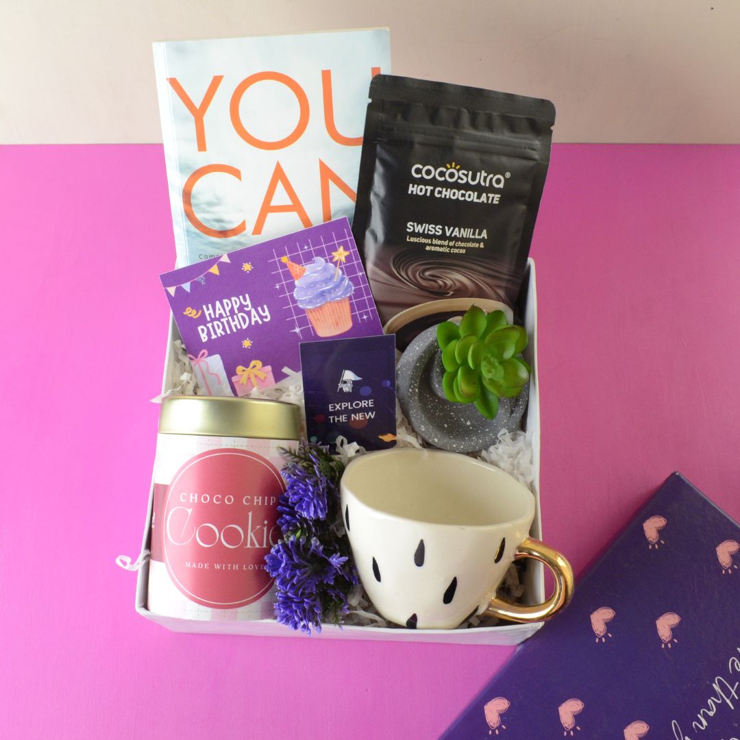 Birthday Bookworm Hamper : This Hamper Contains : “You Can” Bestselling book, Magnetic Bookmark , Ceramic cup with golden handle, Hot chocolate pack, Choco chip cookie tin ,Circular artificial Succulent plant ,Happy Birthday card , Flower gypsies bunch and Surprise heart Box