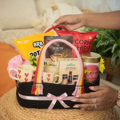 Duo_Delight_Hamper Contains:
Potato Popped Chips Pack,
Coffee Almond Laddoo (pack of 7),
Popped Corn Chips Pack,
Choco-chip Cookie Tin,
MCaffeine Body Detan Kit,
Set of Heartshape Ceramic 2 Cups,
Artificial Flower bunch,
Rectangular Woven Jute Basket With Loops