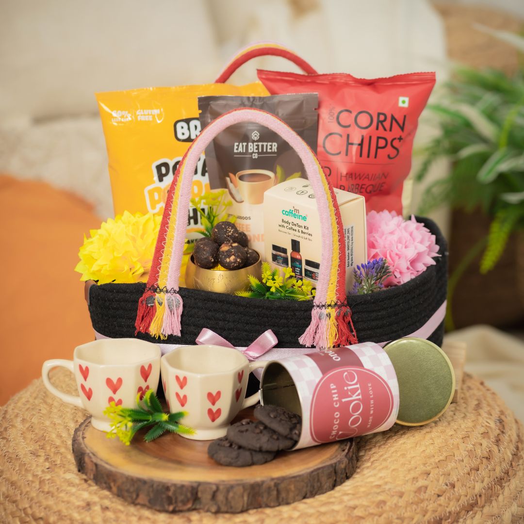 Duo_Delight_Hamper Contains:
Potato Popped Chips Pack,
Coffee Almond Laddoo (pack of 7),
Popped Corn Chips Pack,
Choco-chip Cookie Tin,
MCaffeine Body Detan Kit,
Set of Heartshape Ceramic 2 Cups,
Artificial Flower bunch,
Rectangular Woven Jute Basket With Loops