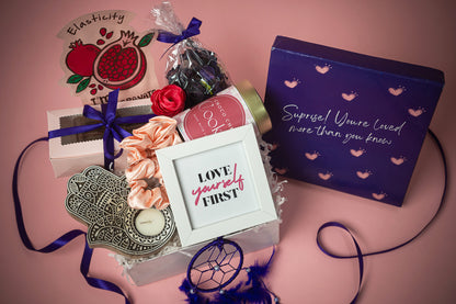 You_are_Loved_Package_Hamper that Contains: Scented Potpourri Pack, Face Mask Sheet ,Chocolate Brownies in Pink Box (2 pieces), Satin Scrunchies (pair of 2) , Choco-chip Cookie Tin Evil Eye Candle Holder, Tea Light Candle, White Photo Frame, Dream Catcher Purple, Premium Gift Box