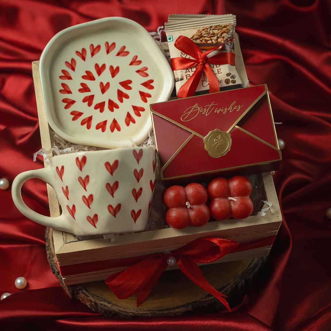 Love in Bloom Hamper Contains: Heart Cup & Saucer set, Almond Brittle (set of 2), Best Wishes Chocolate Box, Pinata Shape Chocolates (5pieces), Mini Scented Bubble Candle (set of 2), Pinewood Crate Basket and Ribbon Bow with a pearl